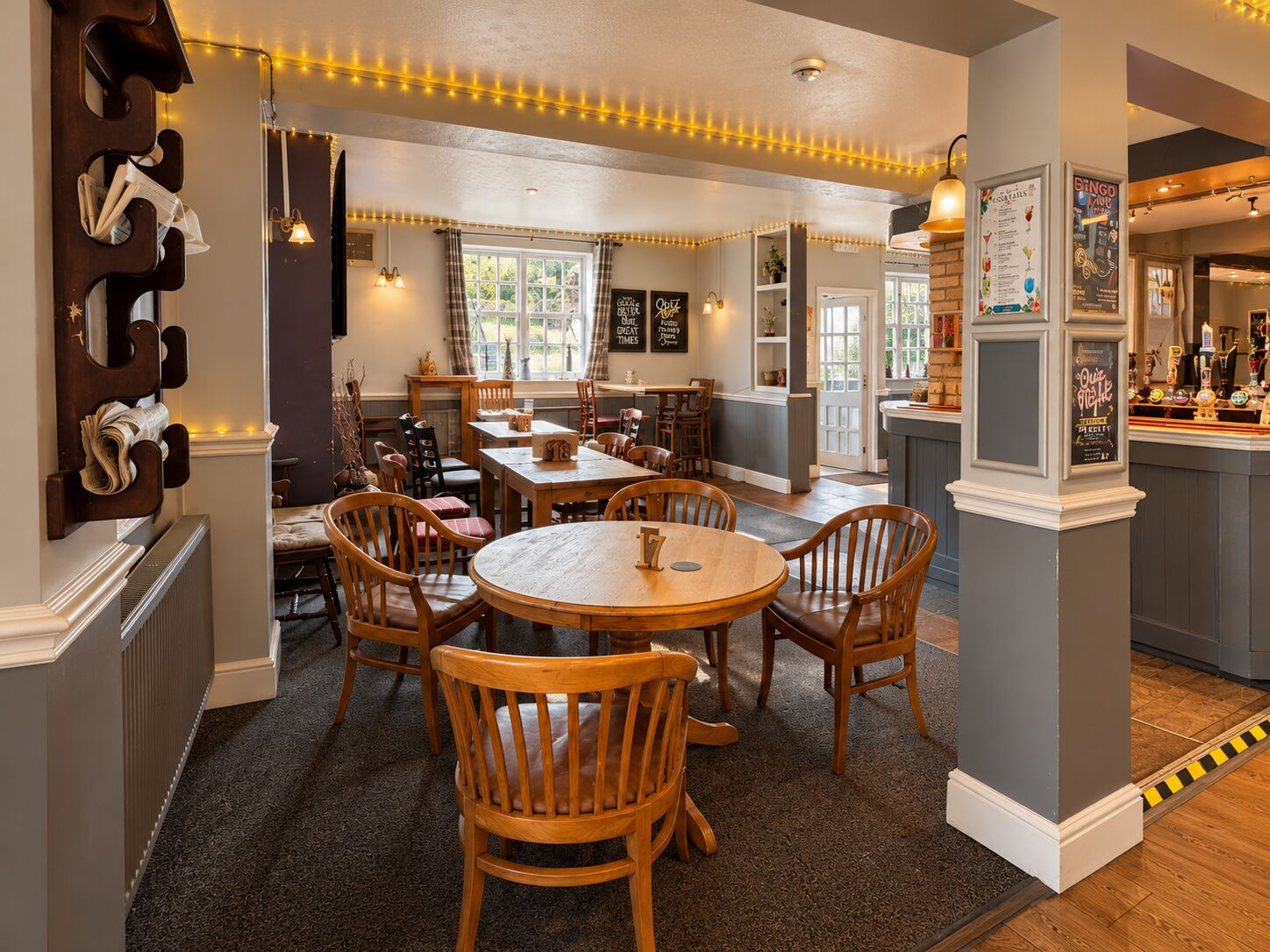 A round wooden table and chairs in the bar lounge at The Barley Mow, with the bar to the right