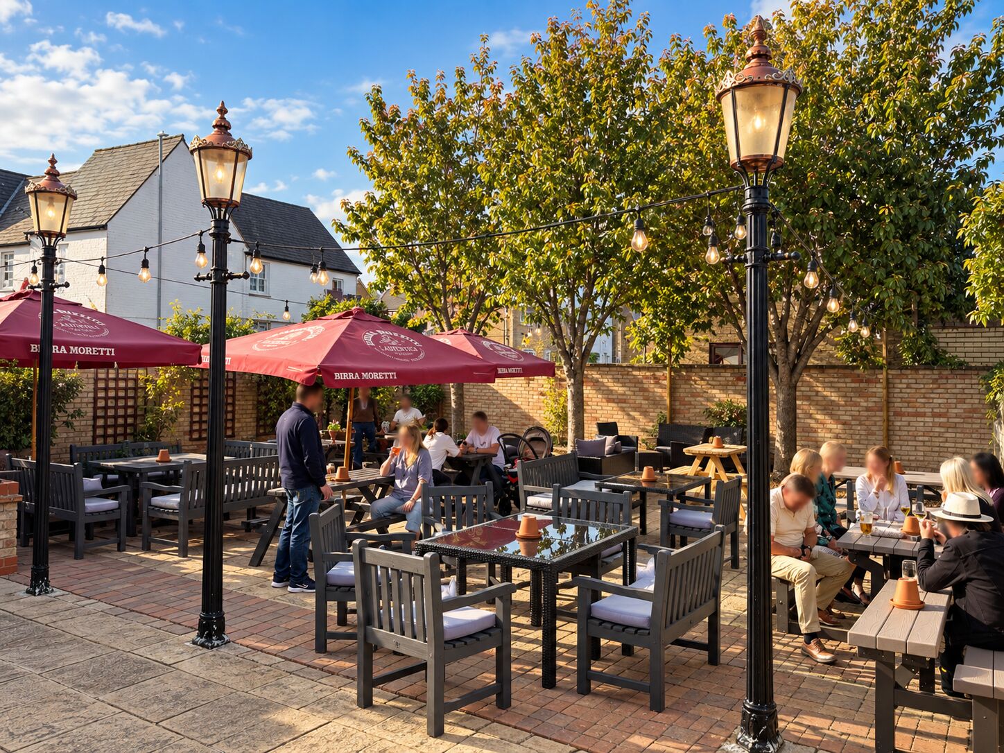 Guests seated at tables beneath red parasols in the courtyard garden at The Barley Mow